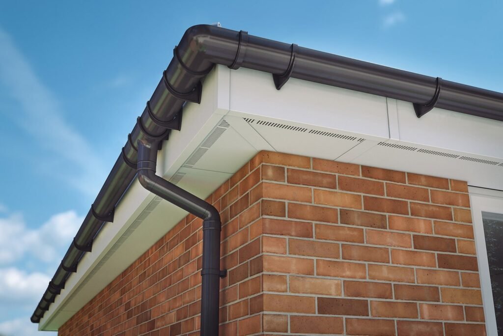 Black guttering and downpipe fitted along a brick house roofline